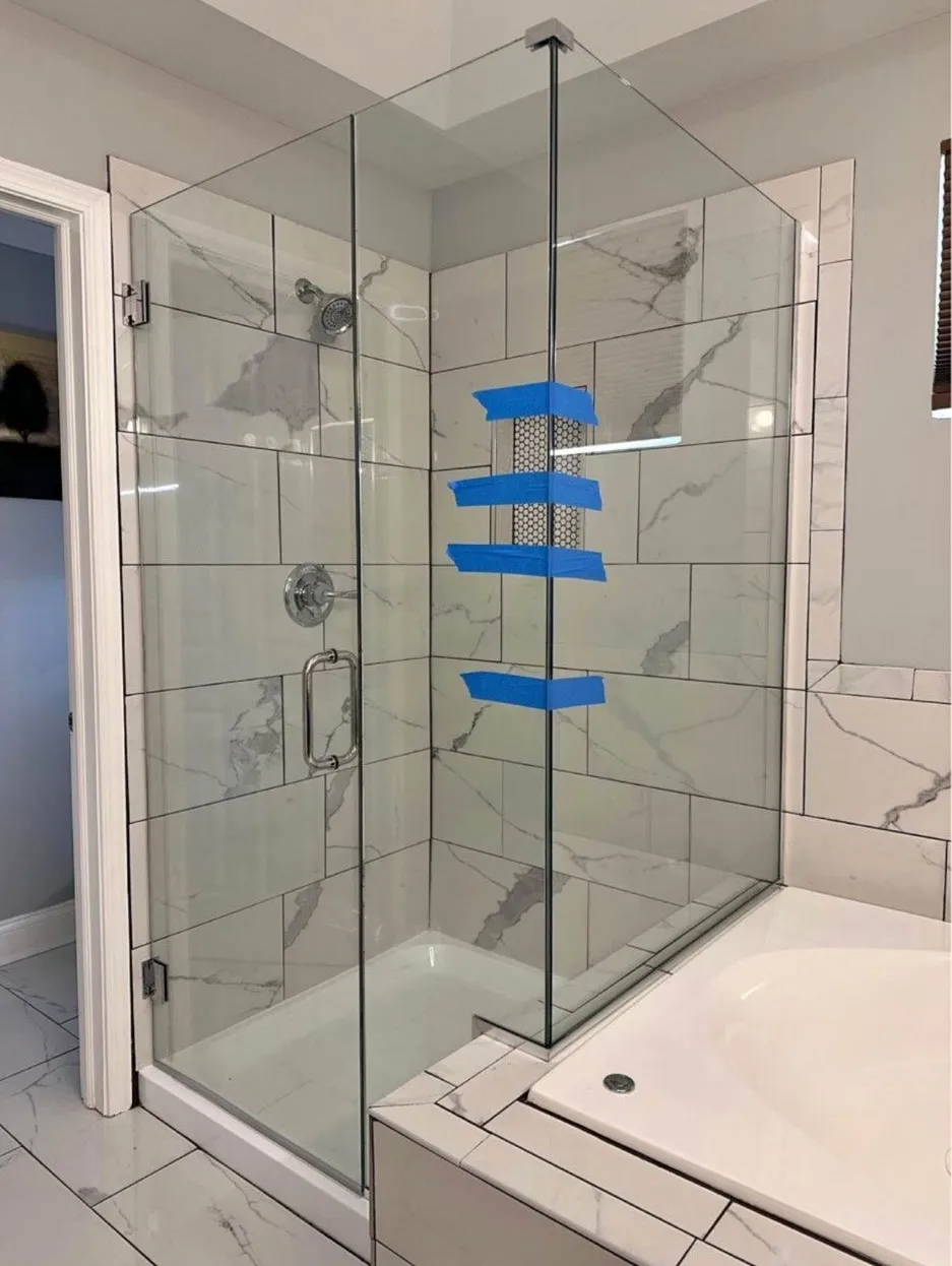 Frameless glass shower enclosure with marble tile