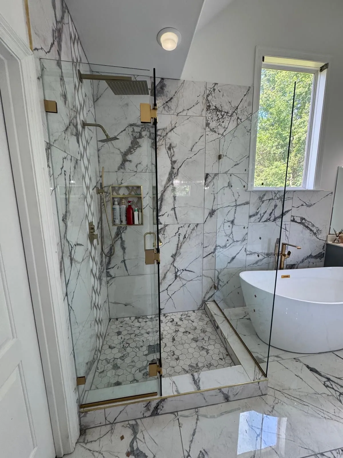 Luxury frameless glass shower with brushed gold hardware by Artix Glass & Cabinetry