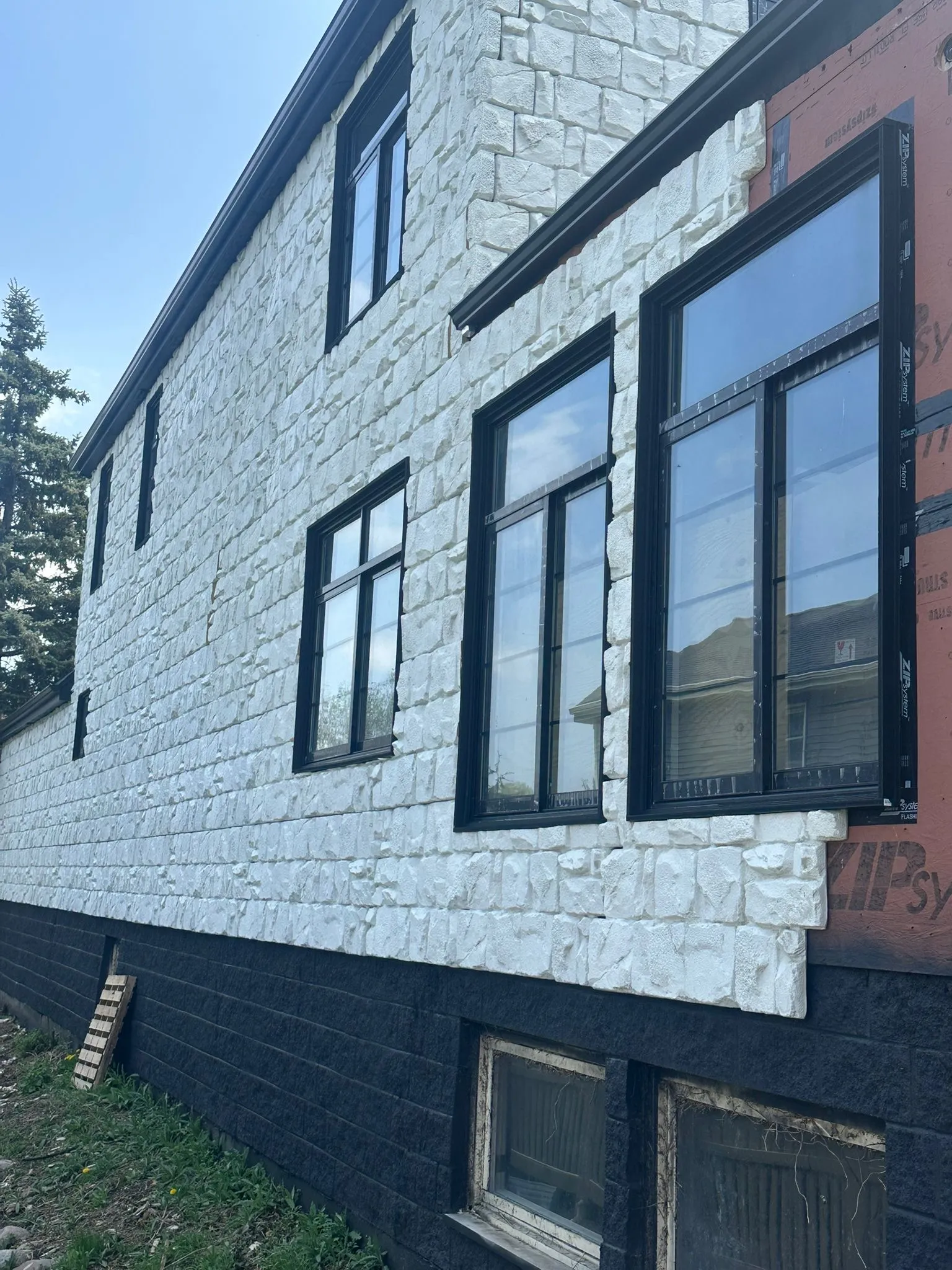 Row of black-frame windows on a white stone-accented home exterior